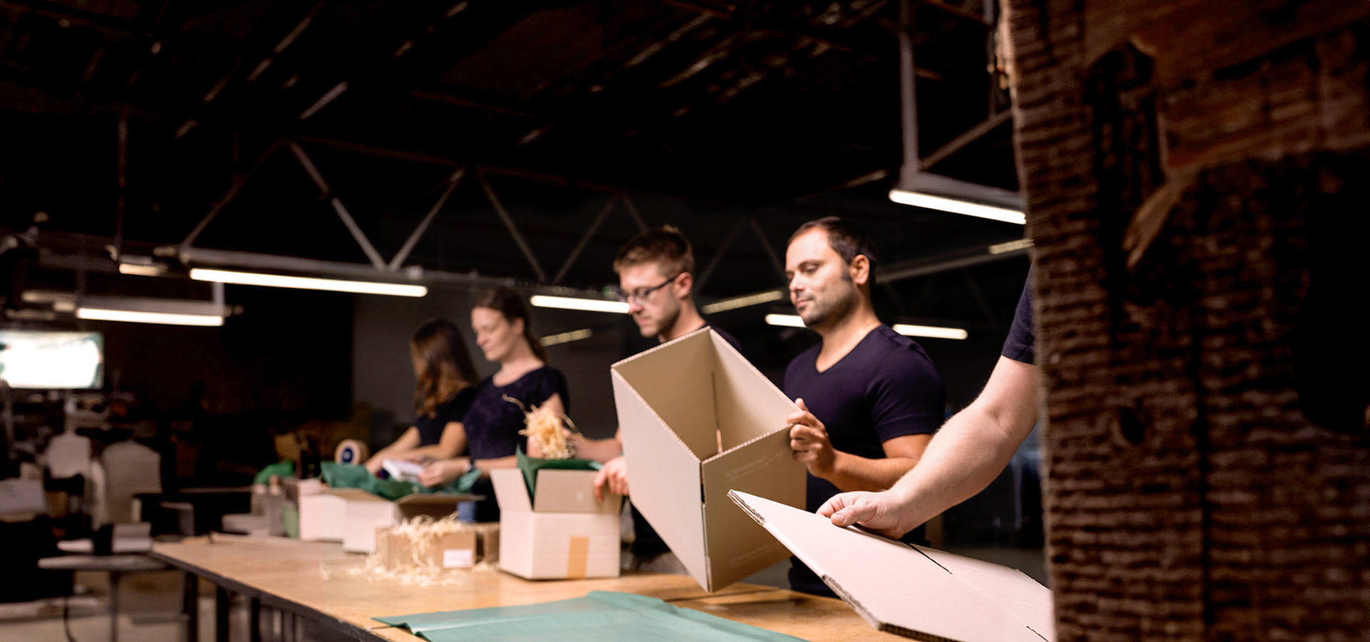 Team packt Kartons im Lager, zeigt die operative Umsetzung von Konfektionierung und Versand im Rahmen von Marketing- und Kampagnenprojekten.